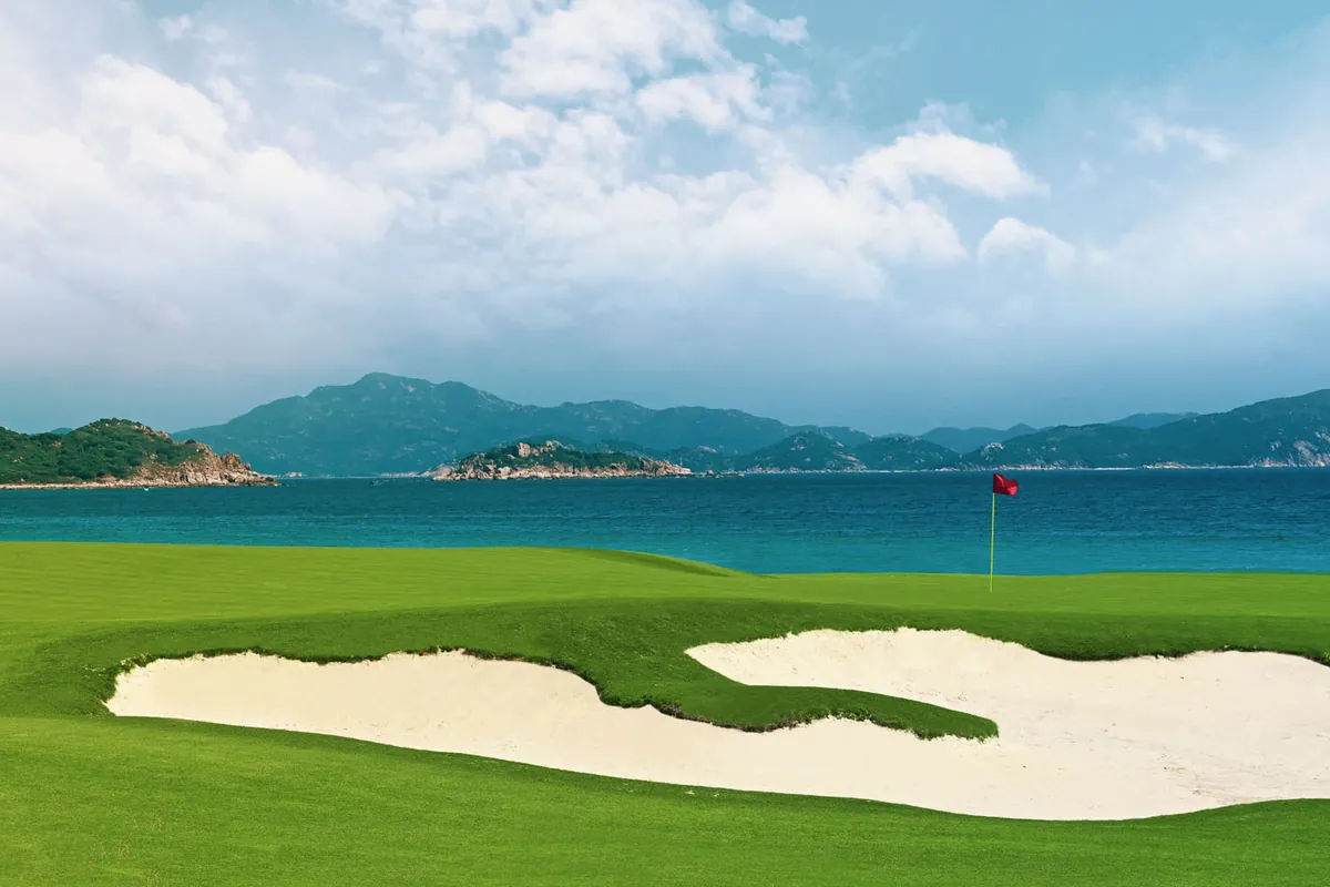 Bunkered fairway and flag above the bay at ANARA Binh Tien Golf Club