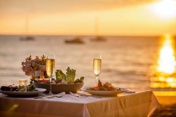 Fine dining table set on the beach at sunset