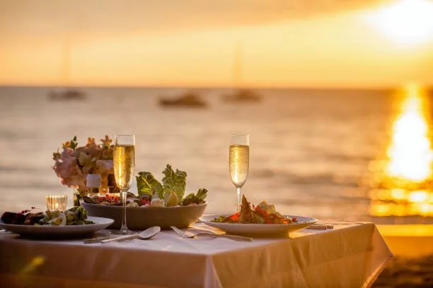 Fine dining table set on the beach at sunset
