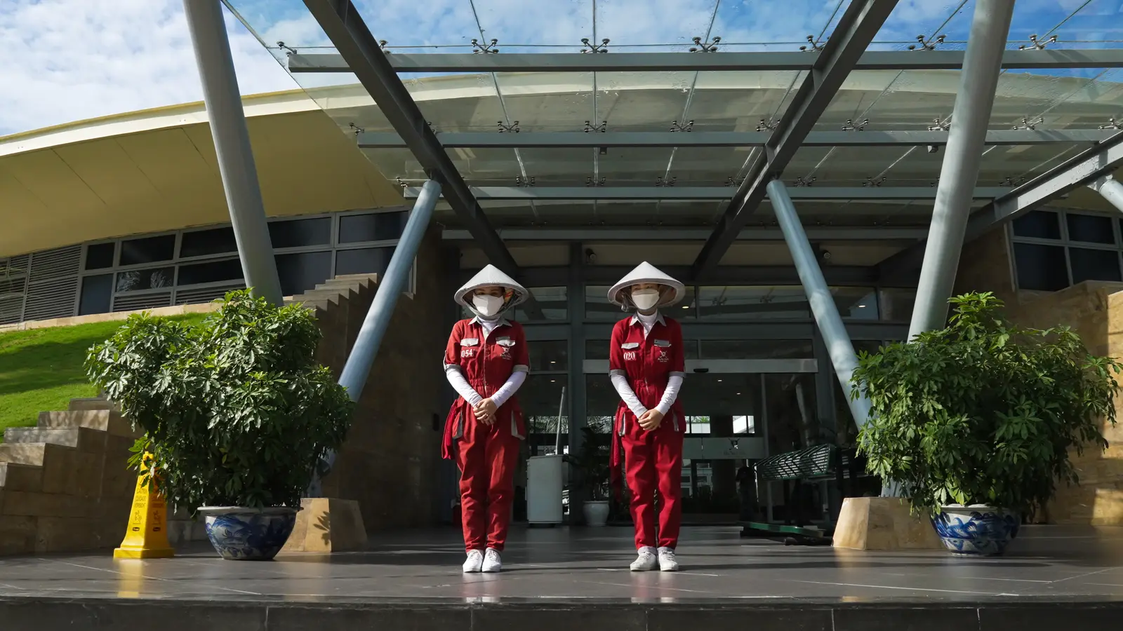 Two caddies in red uniforms and conical hats at the clubhouse