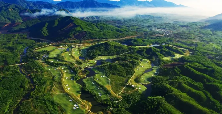 Aerial view of Ba Na Hills Golf Club winding through forested mountain foothills near Da Nang